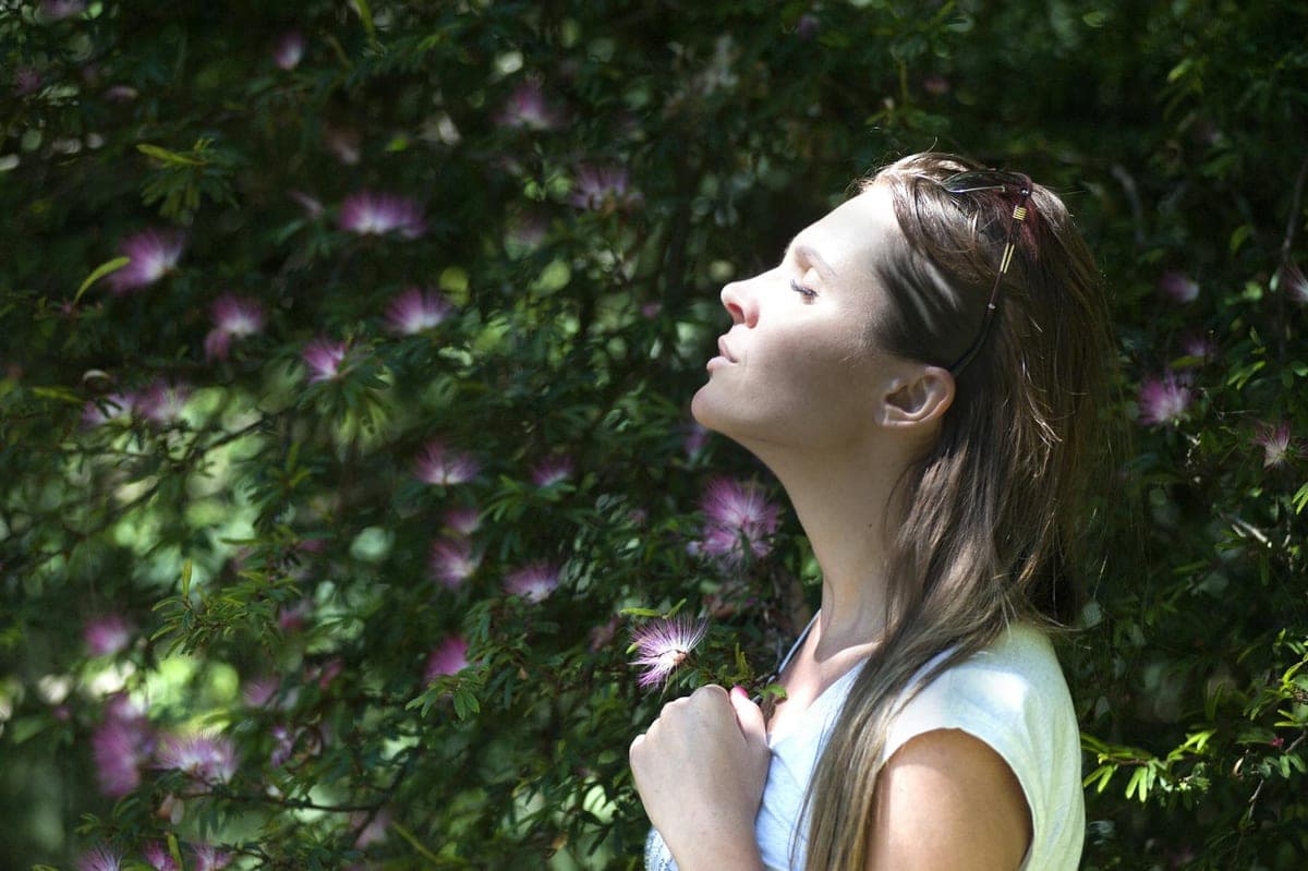 Woman breathing in fresh air surrounded by flowering plants